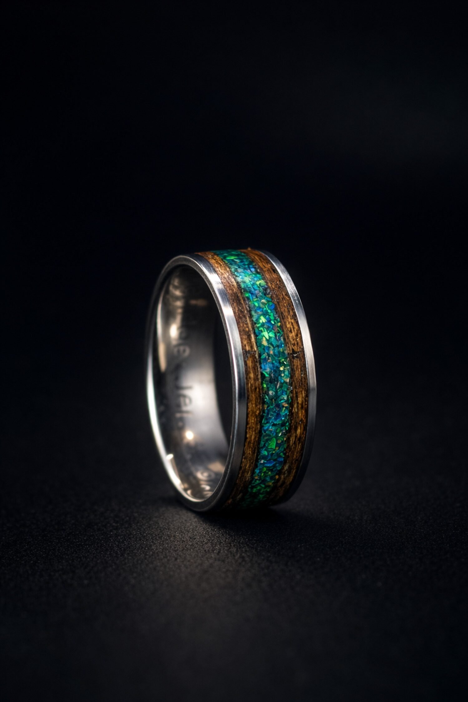 The finished green titanium ring lit against a dark background.