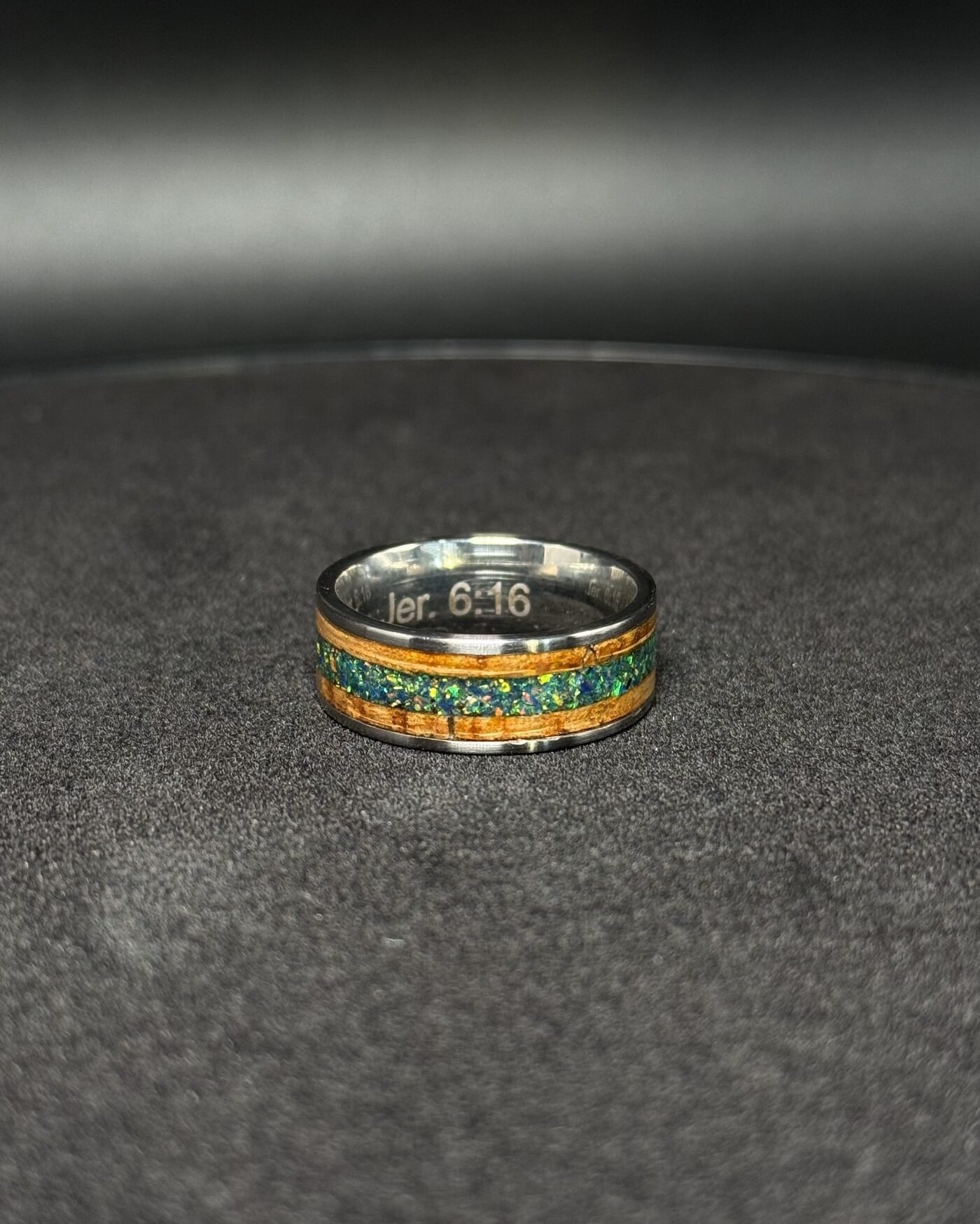 The finished ring on a dark surface, the engraving visible inside the band.