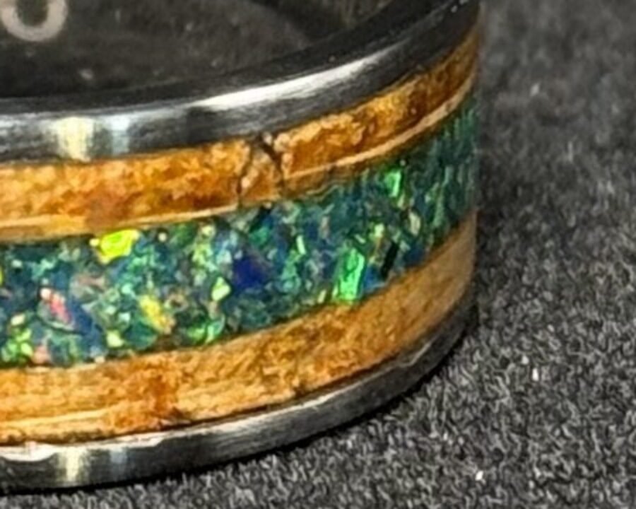 Close detail of the whiskey barrel wood inlay, warm grain either side of the opal.