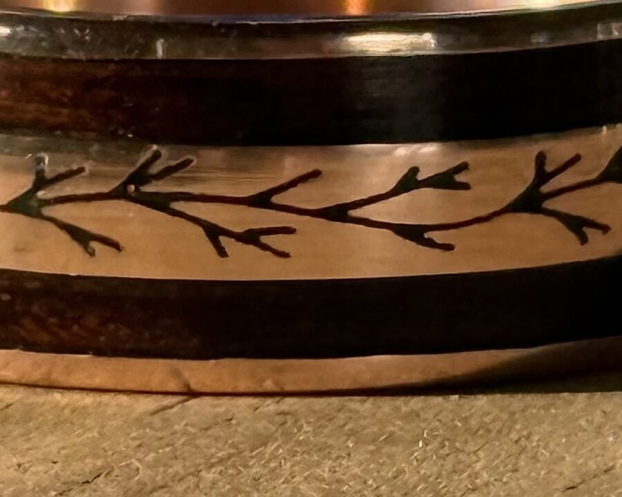 Close detail of the leafy branch engraving cut into the gold centre of the band.